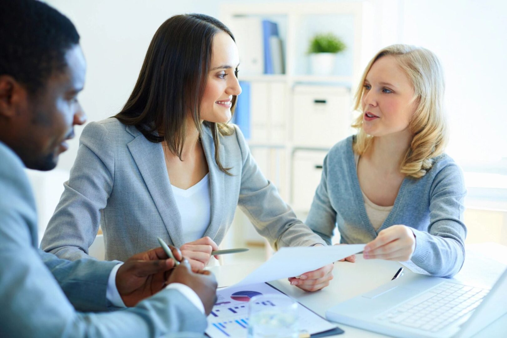 Two women in business suits are talking to a woman.